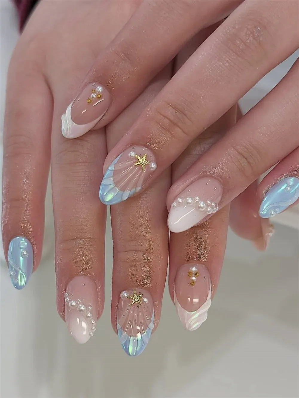Iridescent shell and pearl nails with gold starfish and sheer nude polish