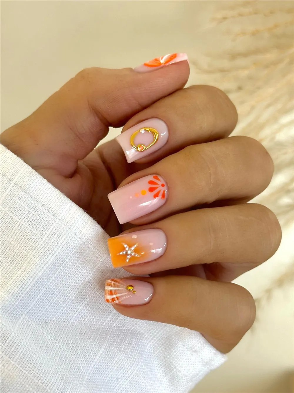 Orange square summer nails with shell art, gold ring accent, and silver starfish