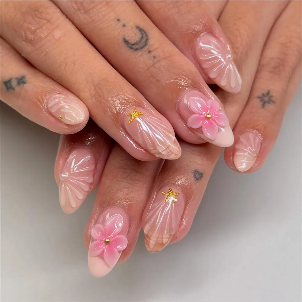 Soft pink almond nails with 3D shell texture, pink flowers, and gold starfish