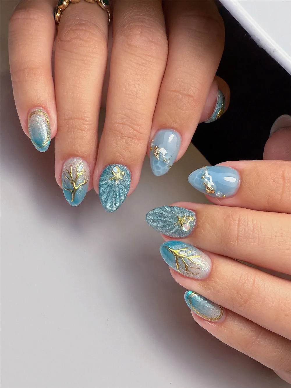 Blue mermaid ocean nails with seashell texture, gold coral branches, pearls, and wave details