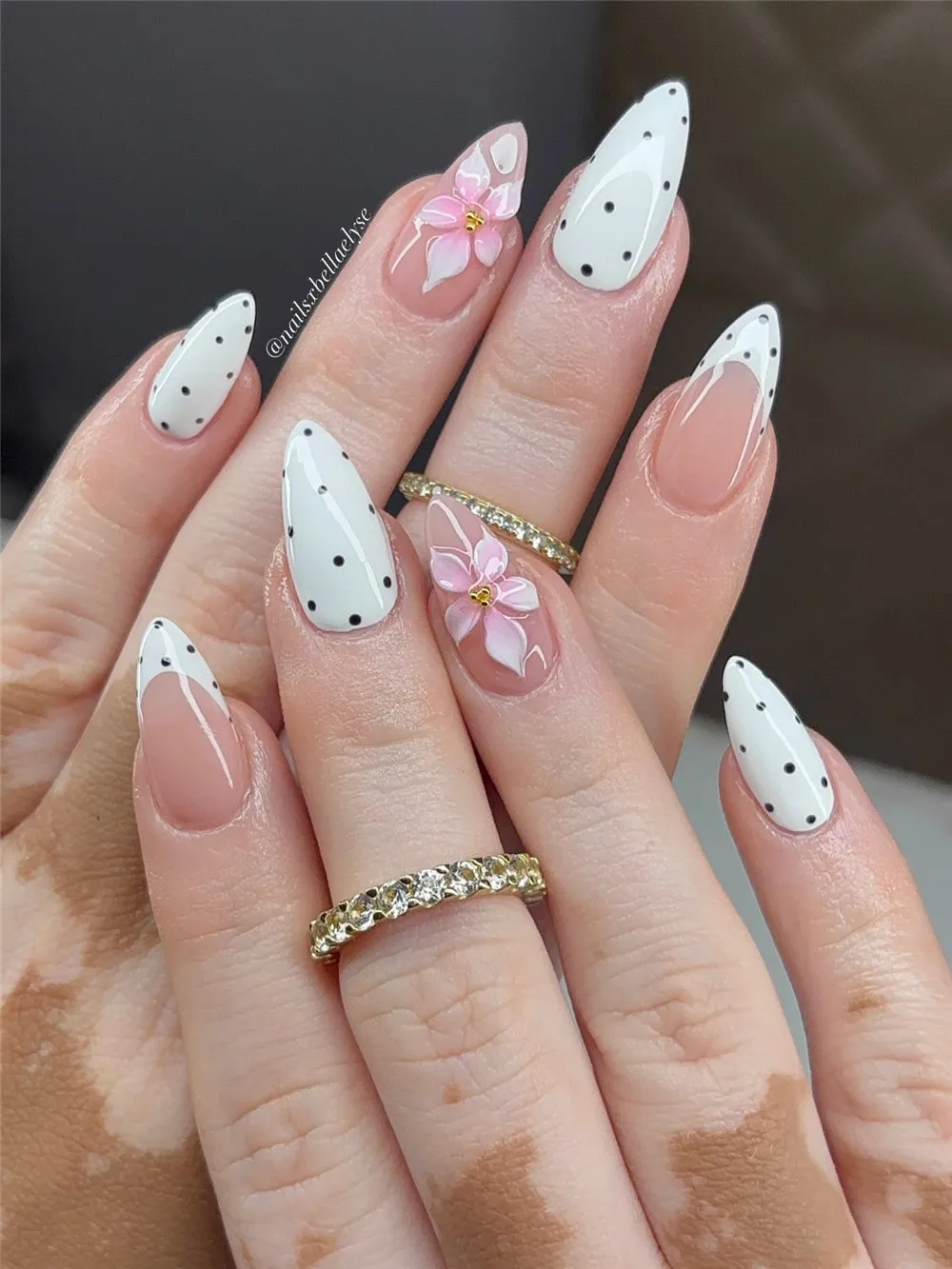 White almond nails with black polka dots and a floral accent