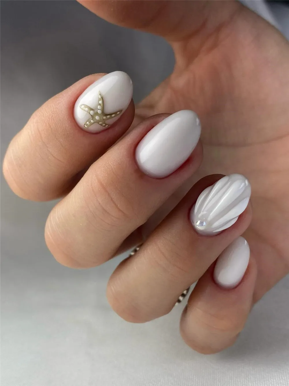 White oval summer nails with a starfish accent and raised shell nail art
