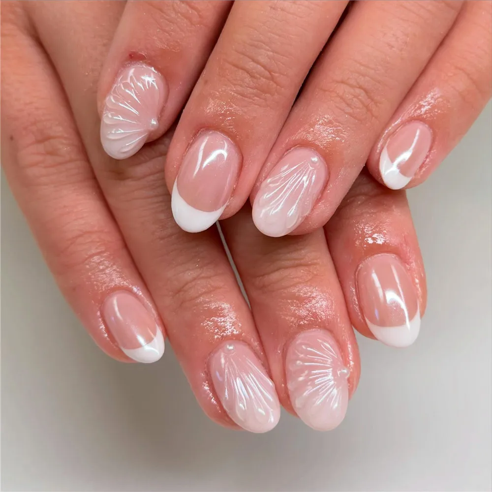 Short white French tip nails with raised shell texture and pearl accents