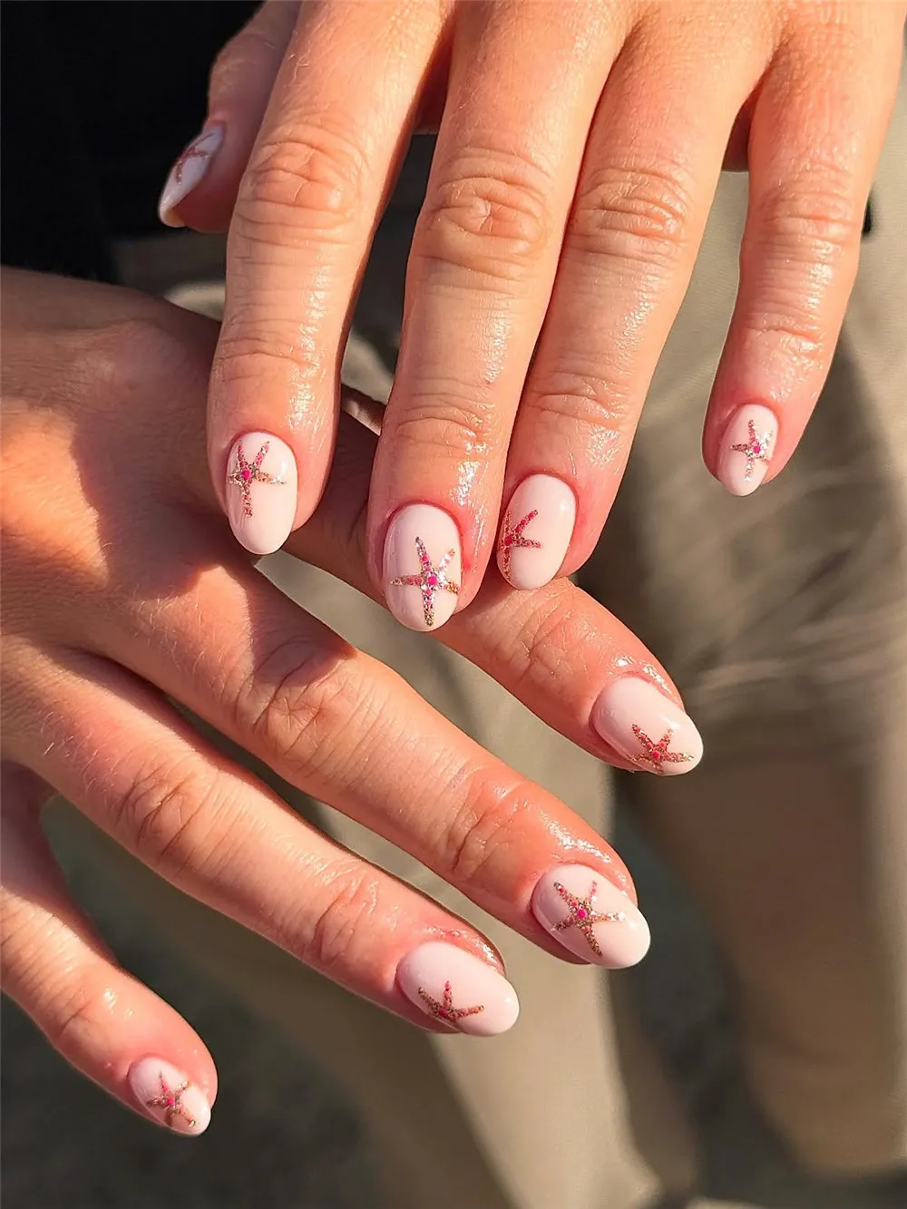 Short milky pink nails with glittery pink starfish on each nail