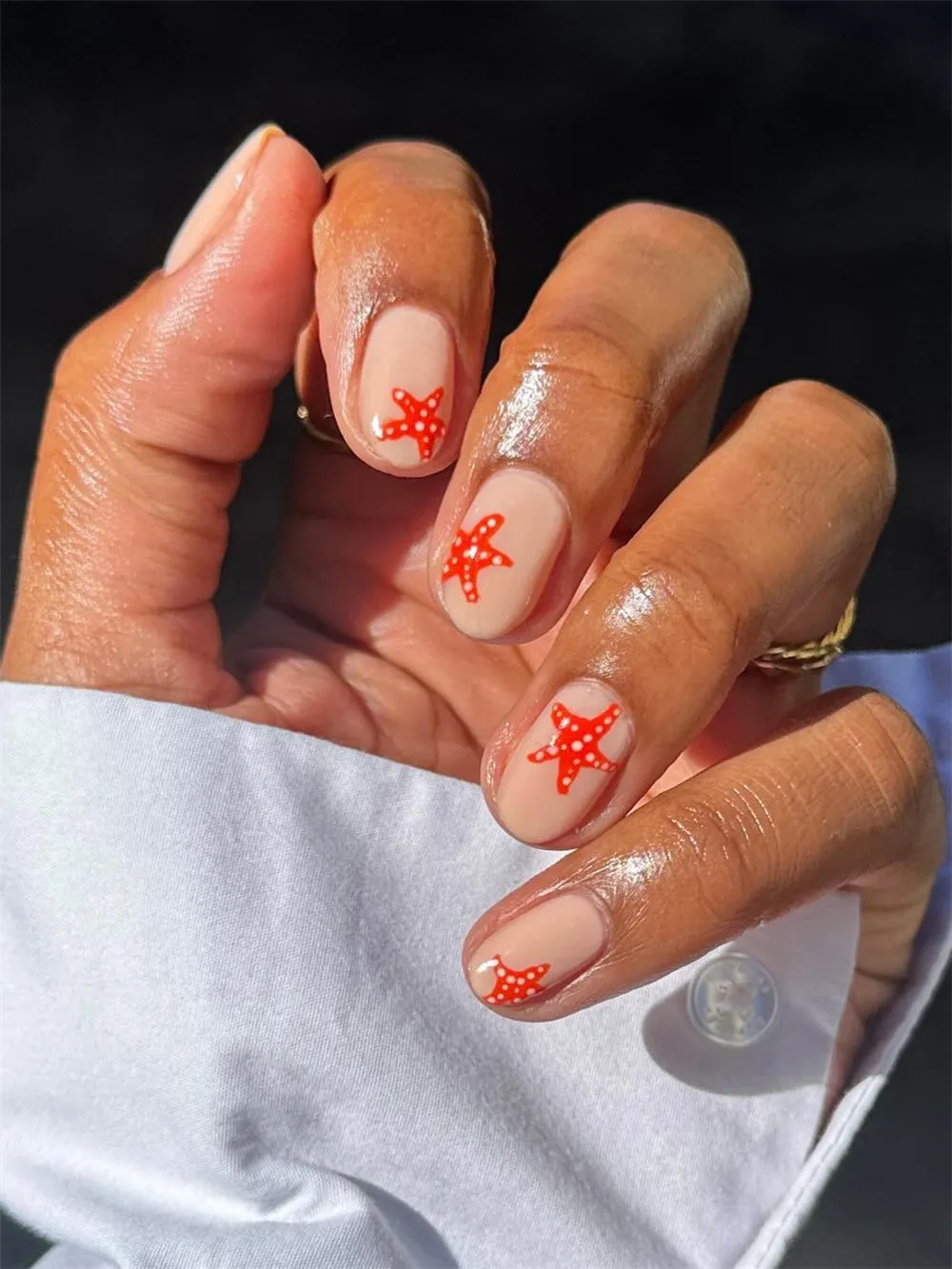Short nude nails with bright orange starfish nail art