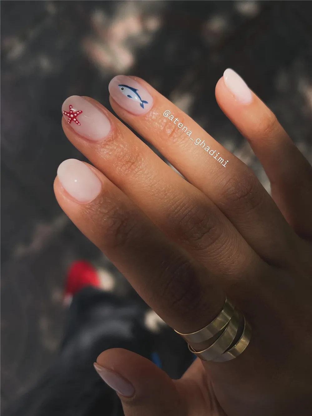 Short milky nails with a red starfish accent and small blue dolphin nail art