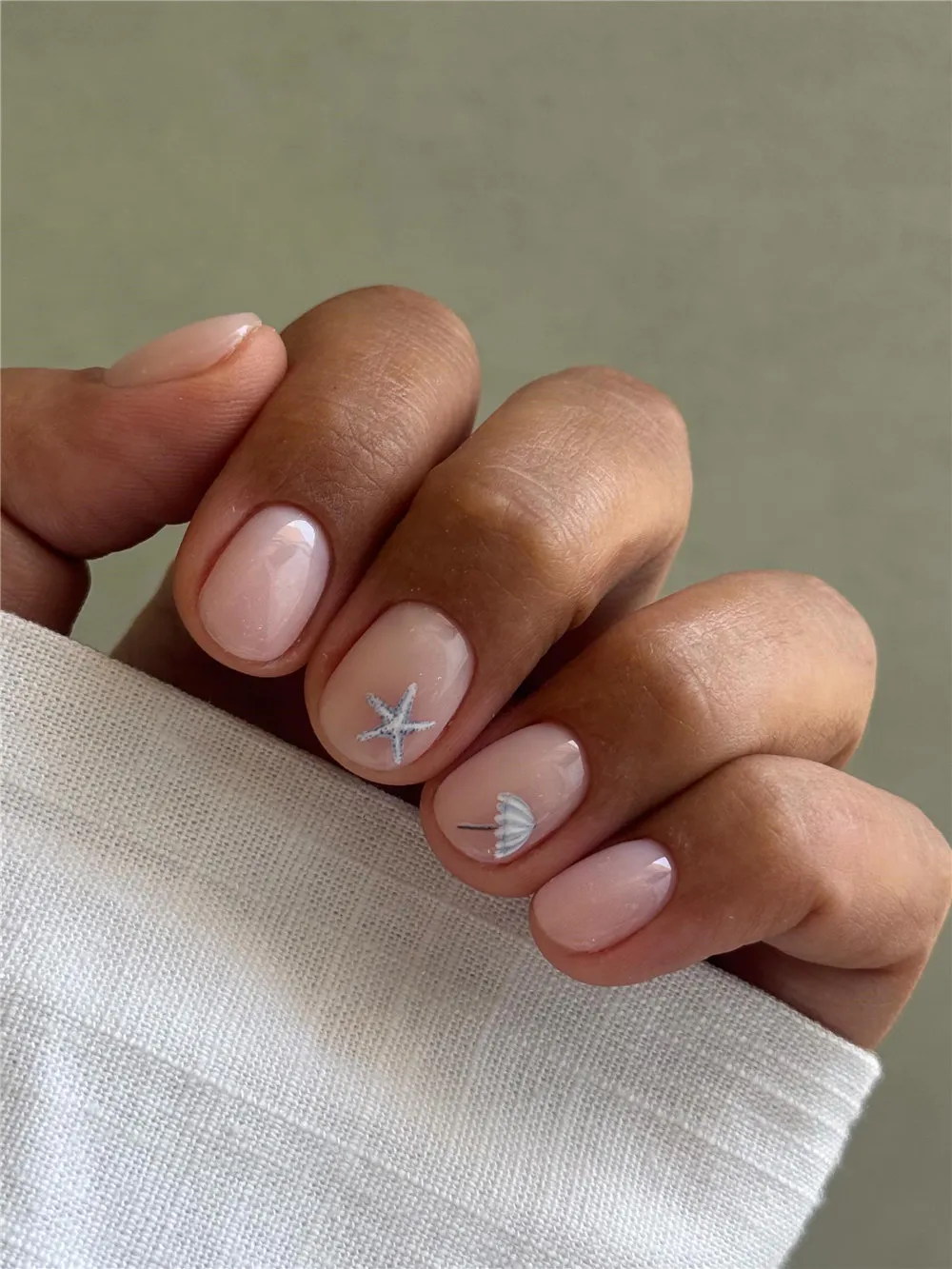 Short sheer pink nails with silver starfish and shell nail art accents