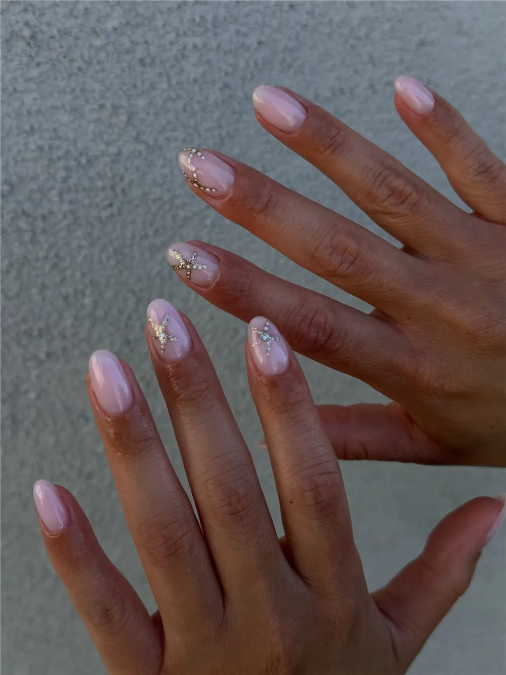 Long almond sheer pink nails with pearl and rhinestone starfish accents