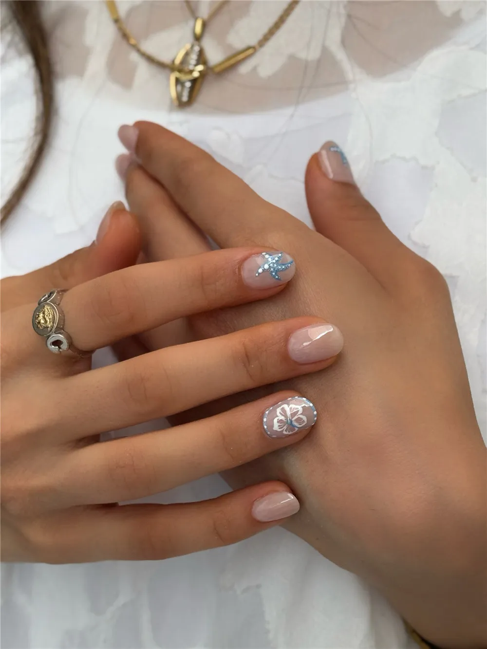 Short neutral nails with soft blue starfish and white flower accent nail art