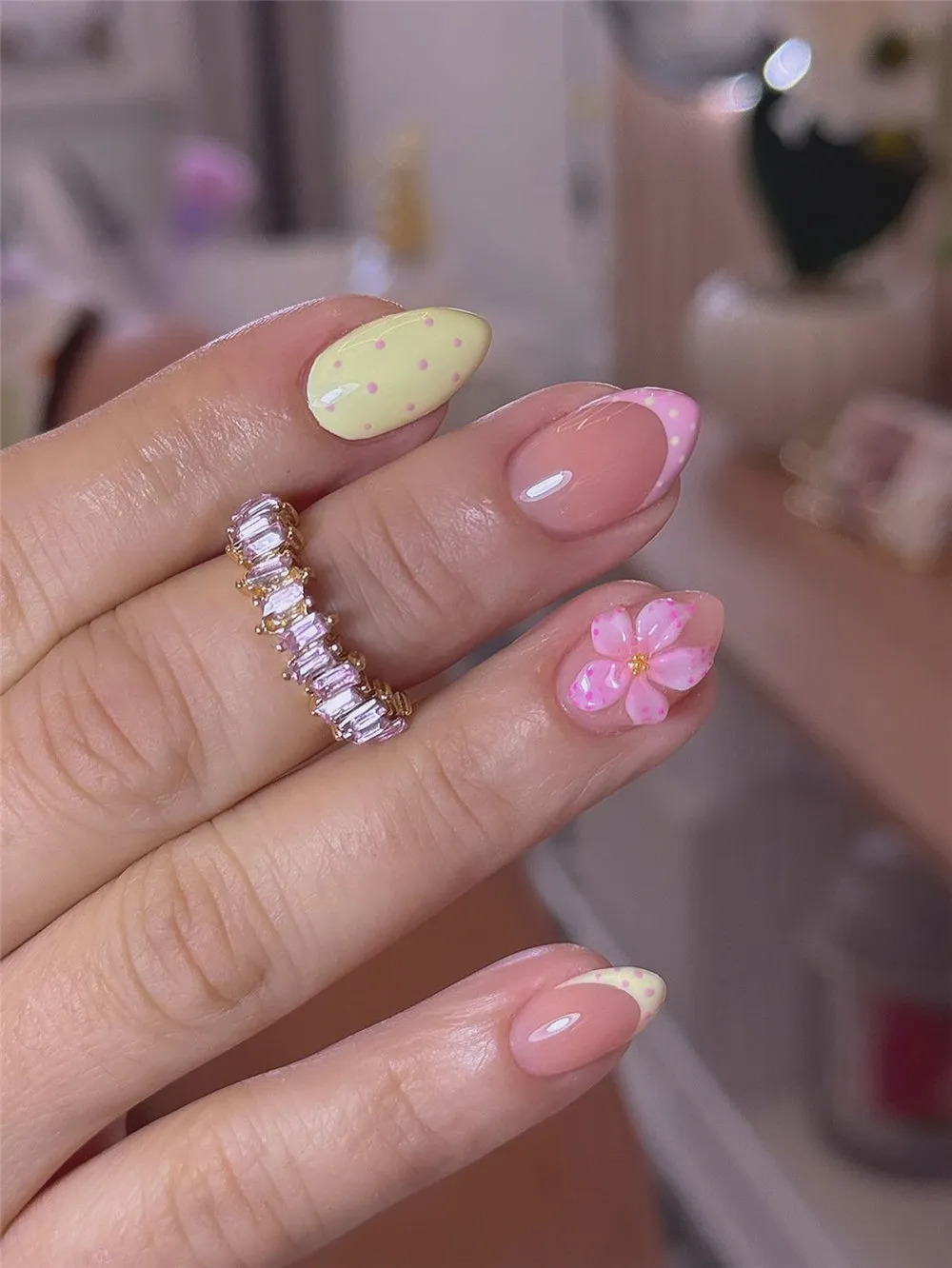 Short almond nails with pastel yellow and pink dotted French tips and a 3D flower