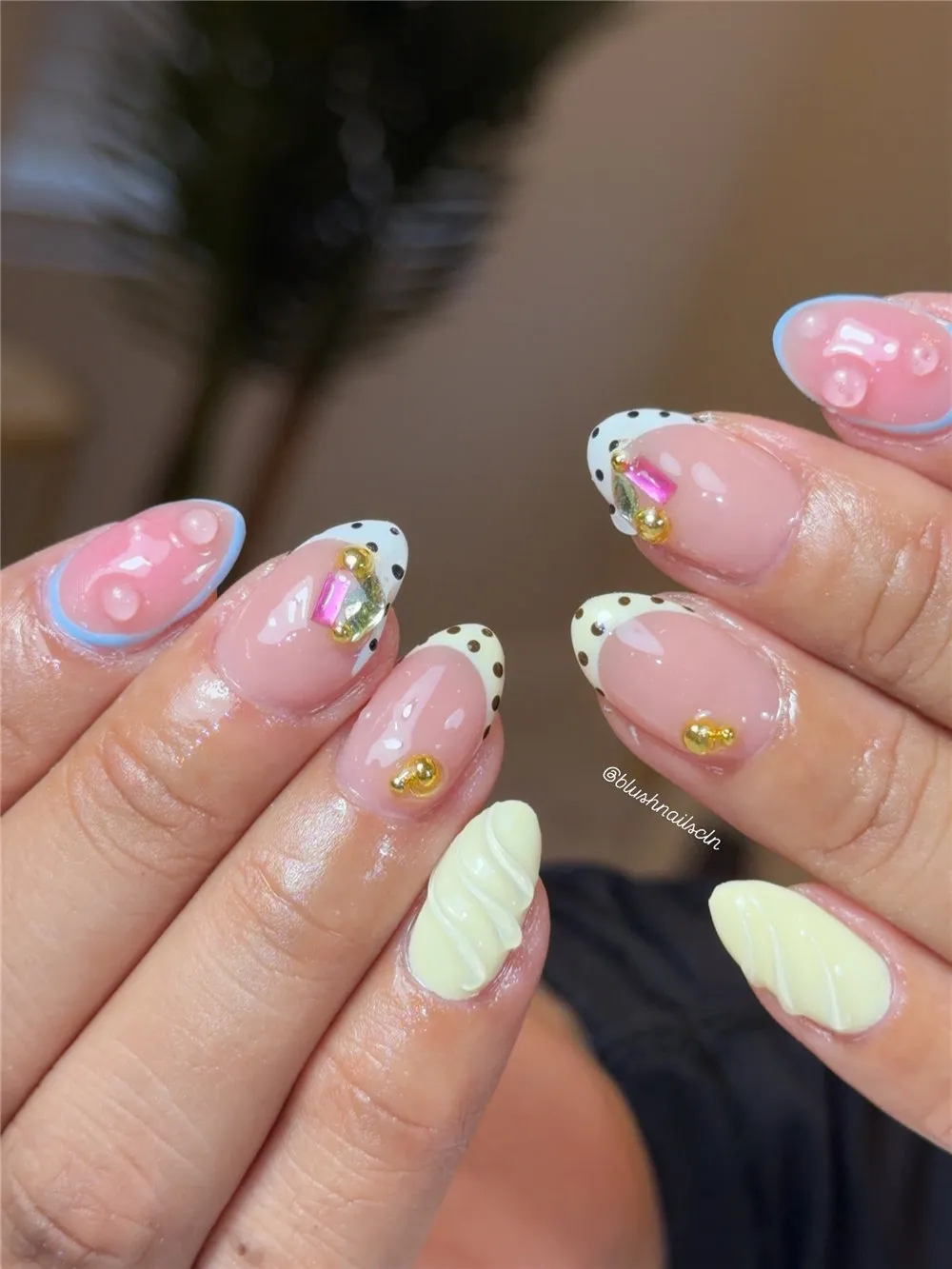 Short French nails with polka dot tips, blue outlines, gold charms, and shell texture