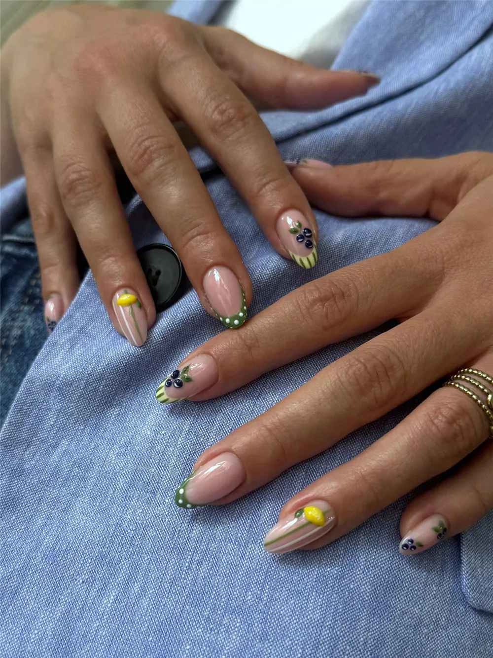 Almond French tips with green dotted tips, lemon accents, blueberries, and striped nail art