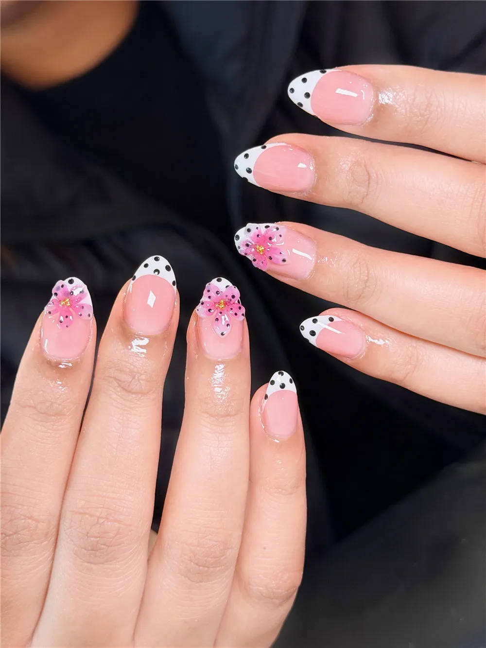 Almond French nails with white tips, black polka dots, and pink 3D flowers