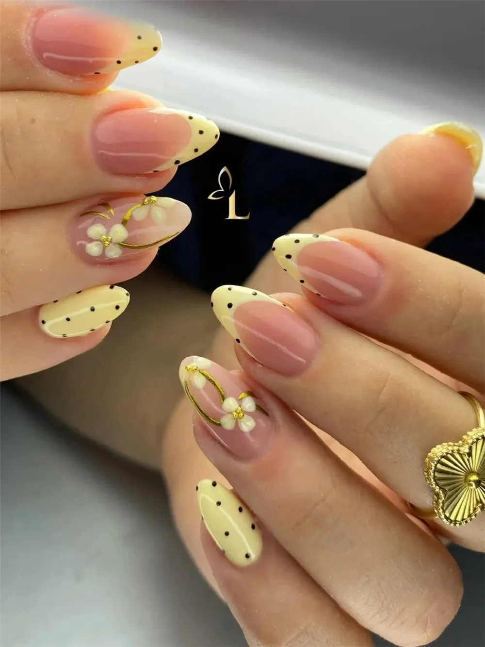 Almond nails with butter yellow dotted French tips, white daisies, and gold line art