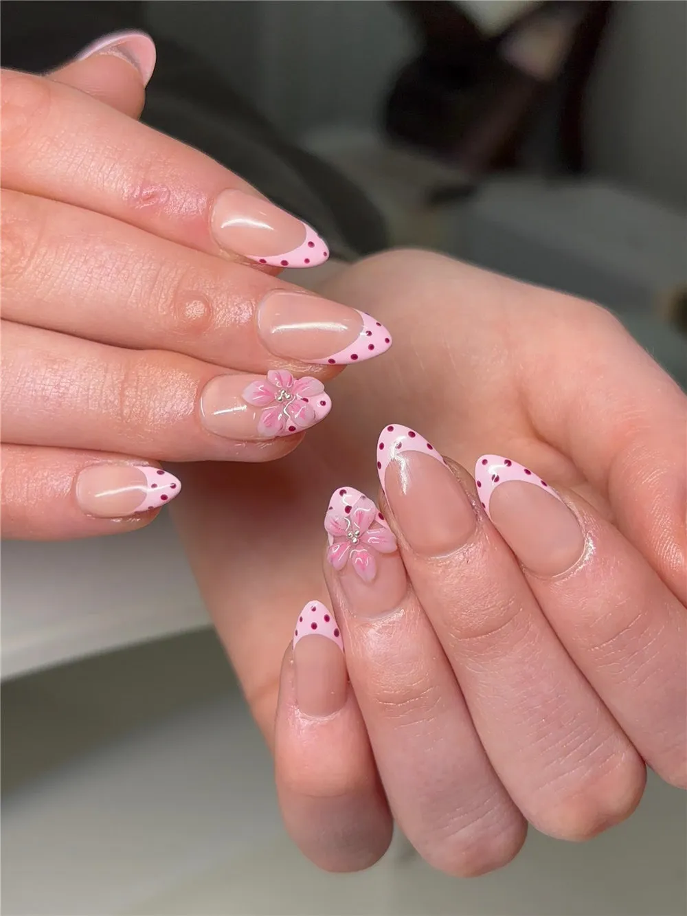 Soft pink French tips with dark pink polka dots and raised pink flower accents
