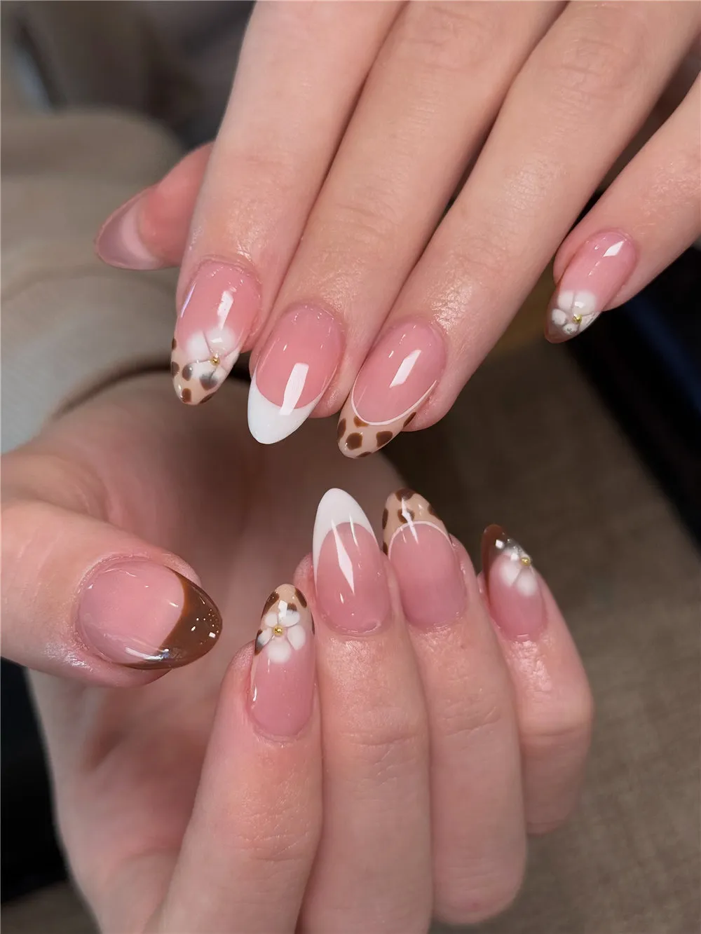 Almond nails with brown and white French tips, dotted accents, and white flowers